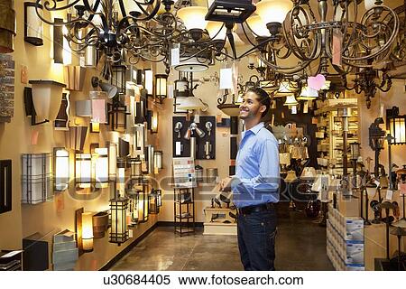 Happy young man browsing for lights fixture in store View Large Photo Image Stock Photography - Happy young man browsing for lights fixture in store. Fotosearch