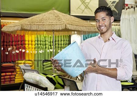 Stock Photo - Happy young man holding a souvenir in store. Fotosearch
