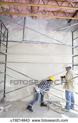 Male and female worker standing under scaffold at construction site View Large Photo Image Stock Image - Male and female worker standing under scaffold at construction site. Fotosearch