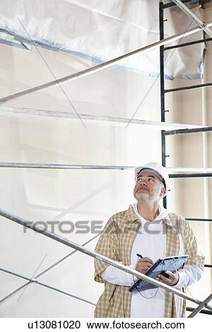 Male architect making a note in digital tablet pc while looking up at construction site View Large Photo Image Stock Image - Male architect making a note in digital tablet pc while looking up at construction site. Fotosearch