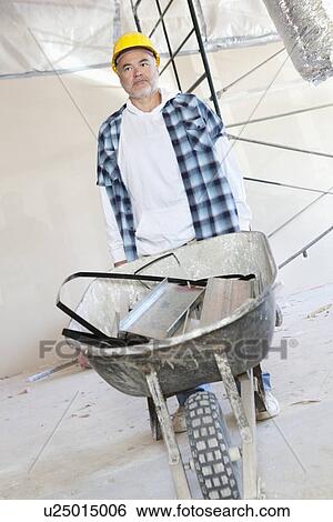 Stock Photograph - Male construction worker standing with a wheelbarrow. Fotosearch