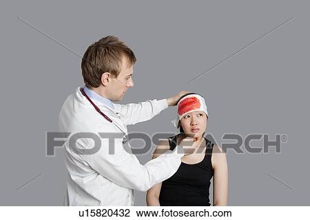 Stock Image - Male doctor treating female patient over colored background. Fotosearch