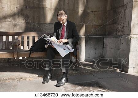 Mature businessman sitting on bench reading newspaper View Large Photo Image Stock Image - Mature businessman sitting on bench reading newspaper. Fotosearch