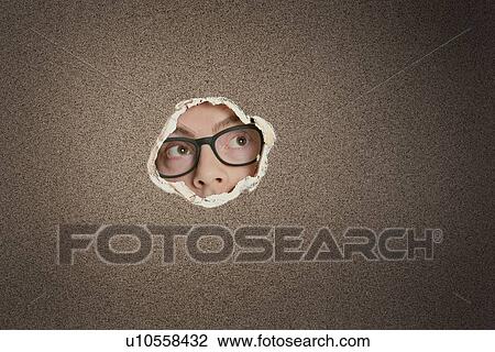 Stock Image - Mid adult Caucasian man looking away from ripped paper hole. Fotosearch