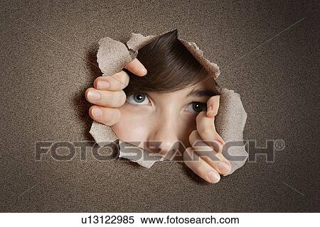 Stock Photography - Middle eastern woman peeking from ripped white paper hole. Fotosearch