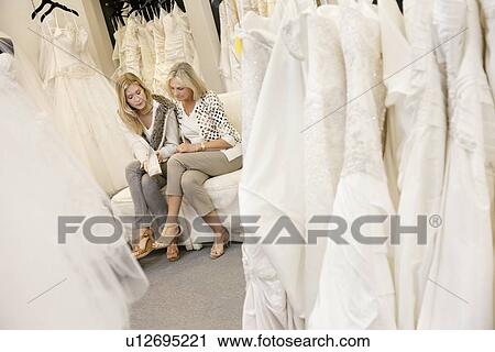 Stock Image - Mother and daughter looking at footwear in bridal store. Fotosearch