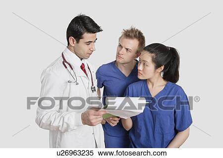 Stock Photography - Multi ethnic healthcare professionals discussing medical report over gray background. Fotosearch