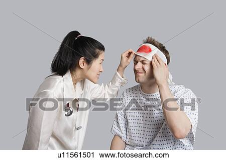 Stock Image - Patient suffering from pain while doctor examining him. Fotosearch