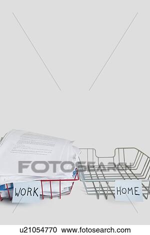 Stock Image - Pile of papers in work tray with empty home platter over white background. Fotosearch