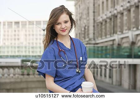 Stock Photo - Portrait of a beautiful young female doctor having a coffee break. Fotosearch
