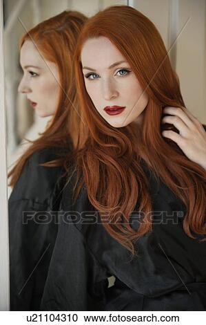 Stock Image - Portrait of a beautiful young woman in robe with hand in hair. Fotosearch