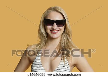 Portrait of a beautiful young woman in bikini wearing sunglasses over colored background View Large Photo Image Stock Photo - Portrait of a beautiful young woman in bikini wearing sunglasses over colored background. Fotosearch