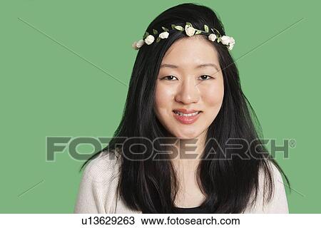 Stock Image - Portrait of a beautiful young woman wearing a hair wreath over green background. Fotosearch