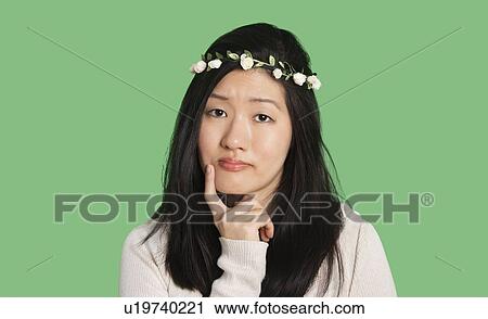 Portrait of a beautiful young woman thinking with hand on her chin over green background View Large Photo Image Stock Image - Portrait of a beautiful young woman thinking with hand on her chin over green background. Fotosearch