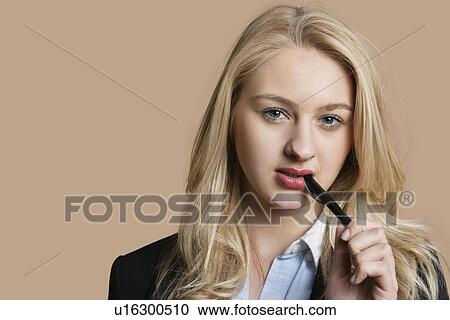 Portrait of a blond business woman with pen in mouth over colored background View Large Photo Image Stock Image - Portrait of a blond business woman with pen in mouth over colored background. Fotosearch
