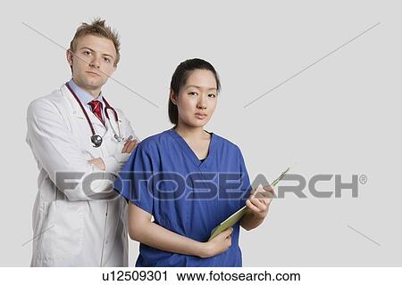 Portrait of a Caucasian doctor standing with an Asian nurse over gray background View Large Photo Image Stock Image - Portrait of a Caucasian doctor standing with an Asian nurse over gray background. Fotosearch
