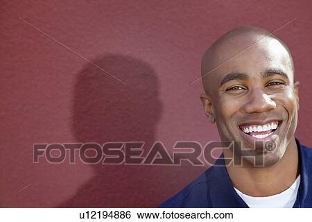 Stock Photograph - Portrait of a cheerful African American man over colored background. Fotosearch