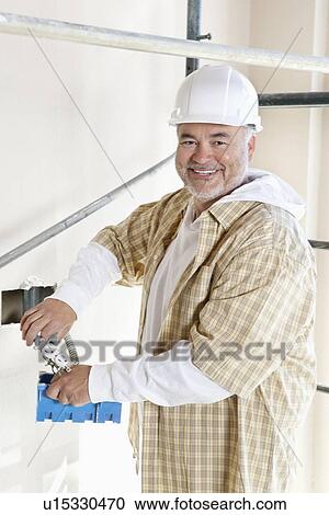 Portrait of a cheerful mature man holding construction equipment View Large Photo Image Stock Image - Portrait of a cheerful mature man holding construction equipment. Fotosearch
