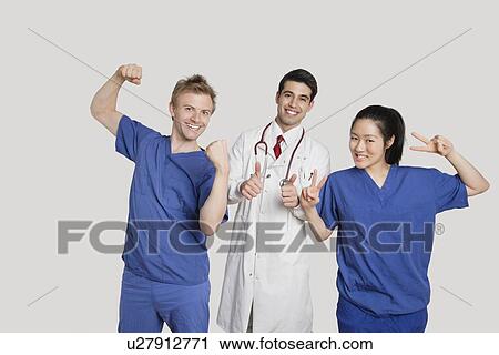 Stock Image - Portrait of a cheerful medical team gesturing over gray background. Fotosearch