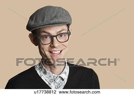 Stock Image - Portrait of a cheerful mid adult man wearing retro glasses over colored background. Fotosearch