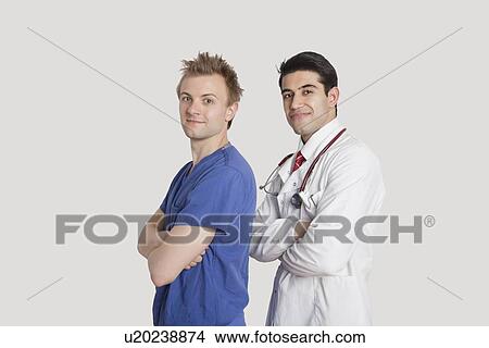 Portrait of a confident doctor and male nurse standing with arms crossed over gray background View Large Photo Image Picture - Portrait of a confident doctor and male nurse standing with arms crossed over gray background. Fotosearch