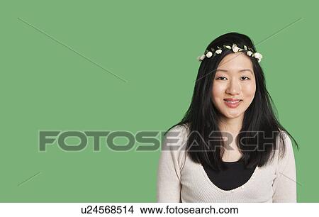 Portrait of a cute young woman wearing a hair wreath over green background View Large Photo Image Picture - Portrait of a cute young woman wearing a hair wreath over green background. Fotosearch