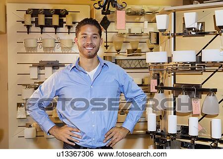 Portrait of a handsome man standing with hands on hips in lights store View Large Photo Image Stock Photograph - Portrait of a handsome man standing with hands on hips in lights store. Fotosearch