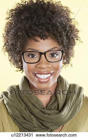 Stock Image - Portrait of a happy African American woman wearing glasses with a stole round her neck over colored background. Fotosearch