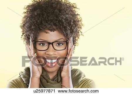 Stock Image - Portrait of a happy African American wearing glasses over colored background. Fotosearch