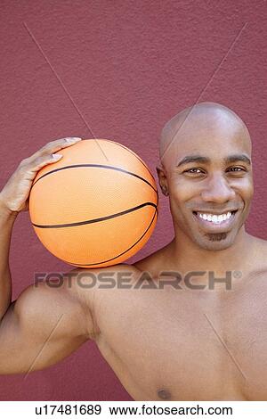 Portrait of a happy African American man with basketball on shoulder over colored background View Large Photo Image Stock Photo - Portrait of a happy African American man with basketball on shoulder over colored background. Fotosearch