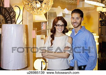 Portrait of a happy couple standing together in lights store View Large Photo Image Stock Photo - Portrait of a happy couple standing together in lights store. Fotosearch