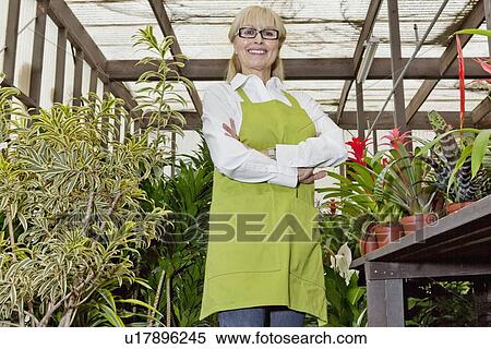Portrait of a happy female gardener standing with arms crossed in botanical garden View Large Photo Image Stock Photography - Portrait of a happy female gardener standing with arms crossed in botanical garden. Fotosearch