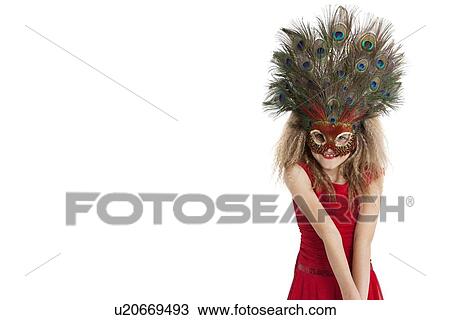 Stock Image - Portrait of a happy girl wearing peacock feather mask over white background. Fotosearch