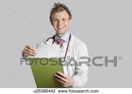 Portrait of a happy male doctor holding a clipboard over gray background View Large Photo Image Stock Image - Portrait of a happy male doctor holding a clipboard over gray background. Fotosearch