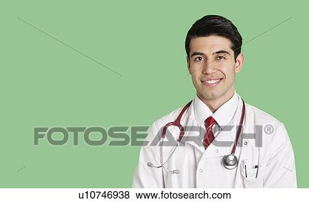 Stock Photo - Portrait of a happy male doctor in lab coat over green background. Fotosearch