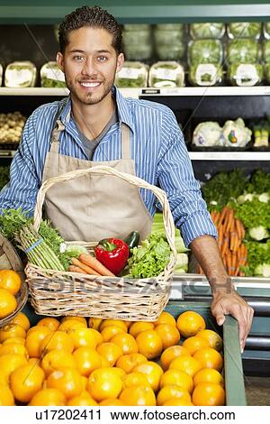 Portrait of a happy man with vegetable basket standing near oranges stall in supermarket View Large Photo Image Stock Image - Portrait of a happy man with vegetable basket standing near oranges stall in supermarket. Fotosearch