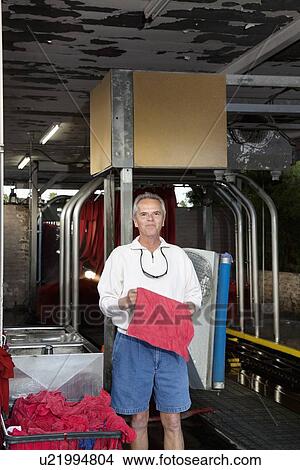 Picture - Portrait of a happy mature owner standing in car wash. Fotosearch