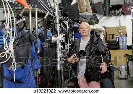 Stock Image - Portrait of a happy senior photographer in studio. Fotosearch