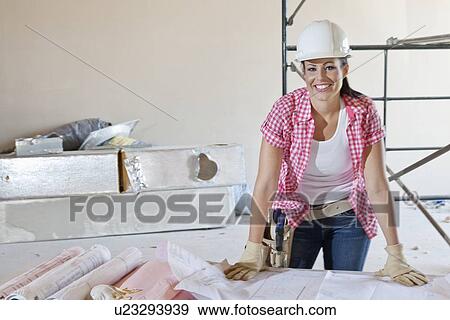 Stock Photo - Portrait of a happy woman architect with building plans. Fotosearch