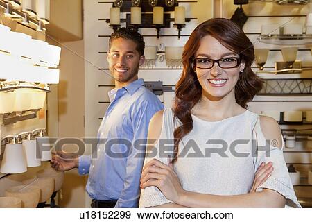 Portrait of a happy woman wearing glasses with arms crossed while man looking in background View Large Photo Image Stock Photo - Portrait of a happy woman wearing glasses with arms crossed while man looking in background. Fotosearch