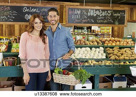 Portrait of a happy young couple in vegetable market View Large Photo Image Stock Photo - Portrait of a happy young couple in vegetable market. Fotosearch