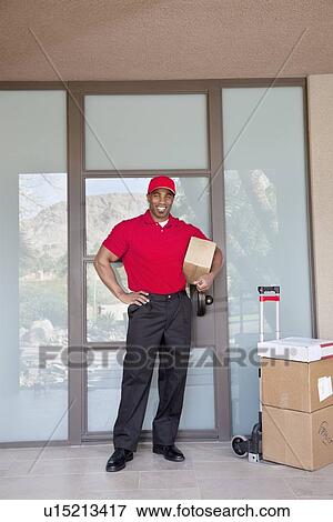 Portrait of a happy young delivery man standing with packages View Large Photo Image Stock Photo - Portrait of a happy young delivery man standing with packages. Fotosearch