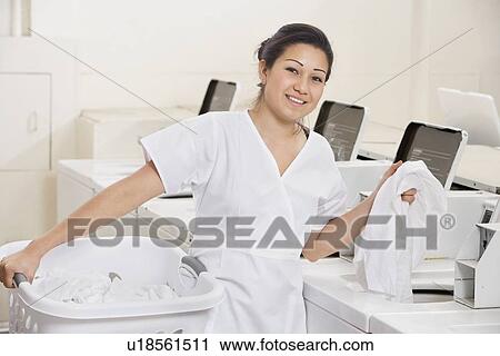 Portrait of a happy young employee putting clothes in washing machine View Large Photo Image Stock Image - Portrait of a happy young employee putting clothes in washing machine. Fotosearch