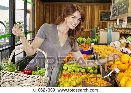 Portrait of a happy young female shopping for fruits in market View Large Photo Image Stock Photo - Portrait of a happy young female shopping for fruits in market. Fotosearch