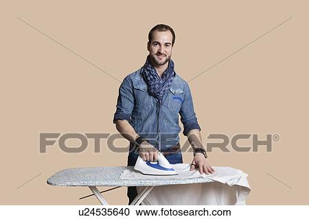 Portrait of a happy young man ironing shirt over colored background View Large Photo Image Stock Image - Portrait of a happy young man ironing shirt over colored background. Fotosearch