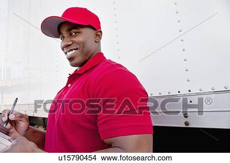 Picture - Portrait of a happy young man with delivery truck in background. Fotosearch