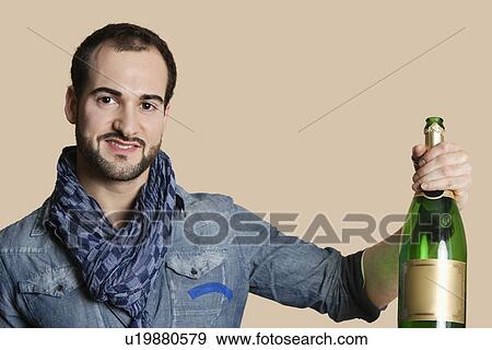 Stock Photo - Portrait of a happy young man with champagne over colored background. Fotosearch
