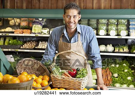 Portrait of a happy young salesman with vegetable basket in supermarket View Large Photo Image Stock Image - Portrait of a happy young salesman with vegetable basket in supermarket. Fotosearch