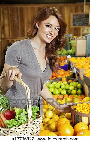 Portrait of a happy young woman shopping in market for fruits View Large Photo Image Stock Image - Portrait of a happy young woman shopping in market for fruits. Fotosearch