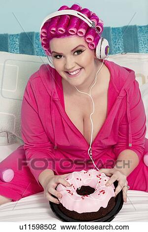 Portrait of a happy young woman wearing headphones sitting on bed with cake View Large Photo Image Stock Image - Portrait of a happy young woman wearing headphones sitting on bed with cake. Fotosearch